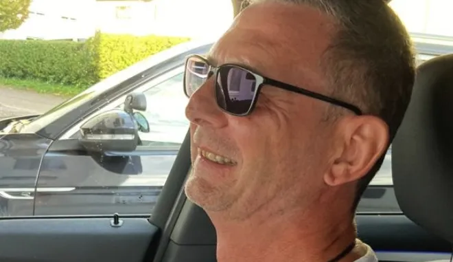 Jürgen Mundil mit Sonnenbrille, lachend im Fahrschulauto